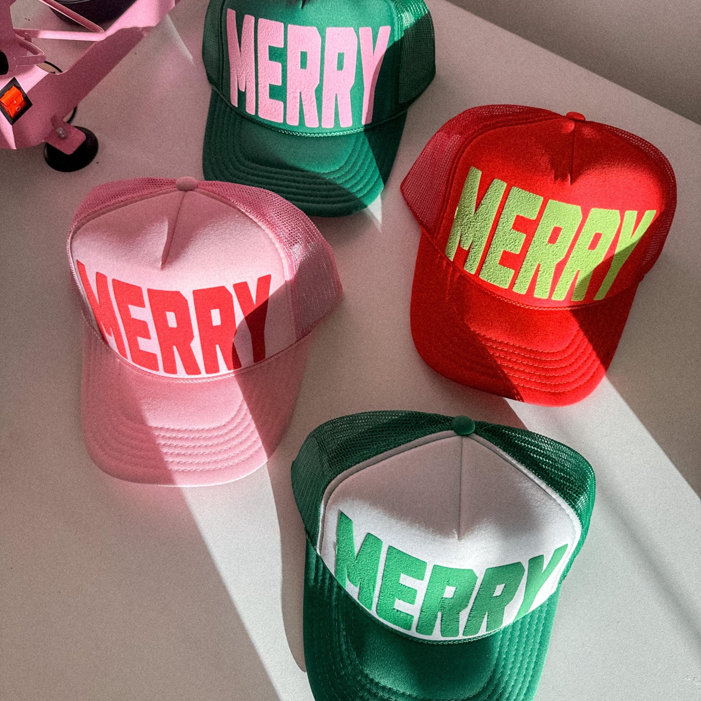 Four colorful caps with 'MERRY' text on a light surface