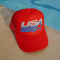Red cap with 'USA' logo on a poolside surface