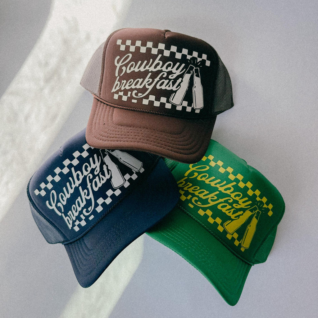 Three baseball caps with 'Cowboy Breakfast' text on a light gray background